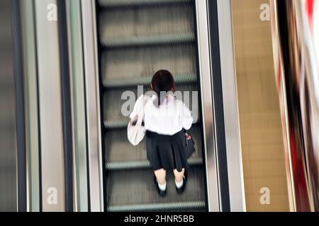 Schüler auf der beweglichen Treppe in Schulkleidung Stockfoto