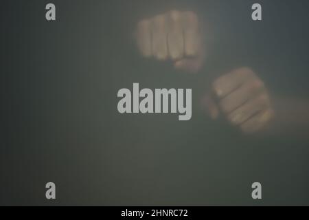 Fäuste hinter Milchglas. Silhouette einer geballten Hände im Nebel Stockfoto