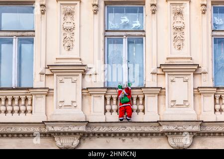 Der weihnachtsmann klettert eine Fassade hinauf Stockfoto