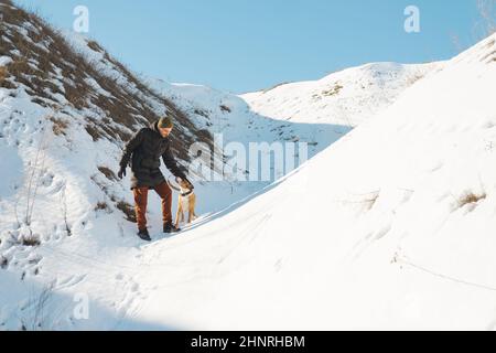 Glücklicher Mann streicheln seinen Hund in verschneite und sonnige Natur. Winter-Scen Stockfoto