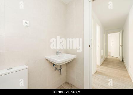 Badezimmer mit weißem Porzellanwaschbecken, Hartholzfußboden in einem langen Flur mit Zugang zu anderen Zimmern Stockfoto