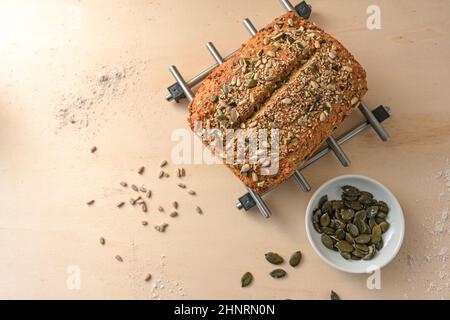 Kürbiskernbrot aus Vollkornmehl mit Körnern und Getreide auf einem Holztisch, hausgemachtes Backen und gesundes Esskonzept, Kopierraum, High-ang Stockfoto