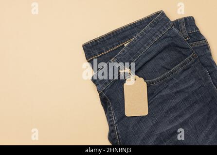 Unbeschriftete rechteckige Pappanhänger an blaue Jeans gebunden. Draufsicht, Kopierbereich Stockfoto