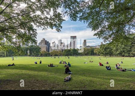 Im Sheep Meadow Central Park in New York entspannen sich die Menschen vor Bäumen Stockfoto