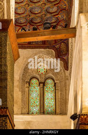 Zwei benachbarte perforierte Stuckbogenfenster mit farbenfrohen Glasmustern im Qalawun-Komplex, Kairo, Ägypten Stockfoto