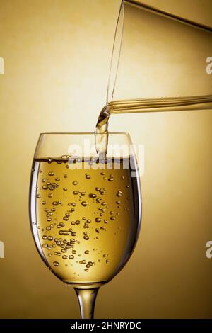 Gießen Sie Weißwein aus einer Karaffe in ein Glas Stockfoto
