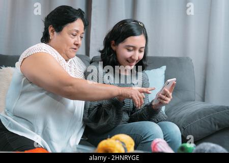 Ältere Frau 60 Jahre alte lateinische Großmutter mit Handy und Spaß mit ihrer Enkelin fotografieren und Videos ansehen Stockfoto