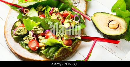 Sommer Vitaminsalat auf Küchenbrett.Avocado-Salat, Tomate mit Knoblauchsauce in Mangold-Blättern. Stockfoto