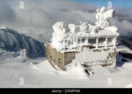 Jasna, Slowakei - 18. Januar 2018: Skilift-Gebäude, mit Antennen auf dem Dach, oben auf dem Chopok-Berg, komplett mit Schnee bedeckt. Starker Wind und Schnee sind im Winter auf den Gipfeln der Nizke Tatry verbreitet. Stockfoto