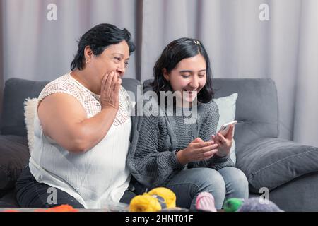 Ältere Frau 60 Jahre alte lateinische Großmutter mit Handy und Spaß mit ihrer Enkelin fotografieren und Videos ansehen Stockfoto