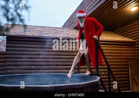Weihnachtsmann testet die Wassertemperatur in der Fritteuse Stockfoto