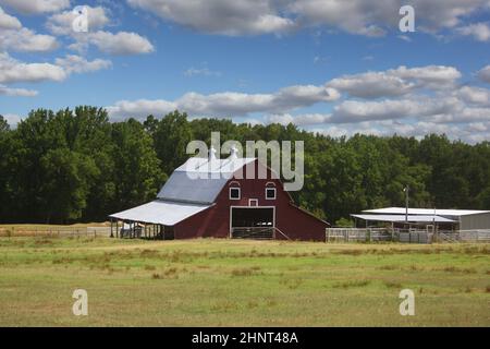 Red Barn befindet sich auf der Farm in Ost-Texas mit blauem Himmel und Wolken Stockfoto