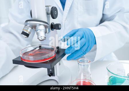 Asian Wissenschaftler Biochemiker oder Mikrobiologe arbeiten Forschung mit einem Mikroskop im Labor. Zum Schutz vor Ausbruch Coronavirus Covid19, Bakterien und Keimen. Stockfoto