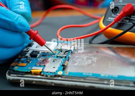 Techniker, der das Innere des Mobiltelefons mit einem Lötkolben repariert. Integrated Circuit. Das Konzept von Daten, Hardware, Technologie. Stockfoto