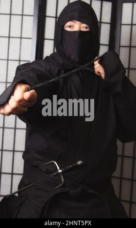 Asian man trägt Ninja Kostüm und hält Ninja Waffen Stockfoto