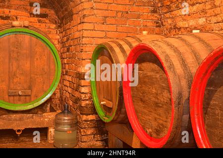 Weinfässer im alten Keller des Weinguts gestapelt. Fässer Wein in einem Weinkeller, einem alten Weinkeller mit gewölbten Ziegeldecken. Traditionelle Weinherstellung Stockfoto