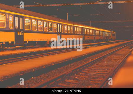 Weißen und Blauen Zug stehend an einem kleinen dachlosen Bahnhof bei Nacht in der Tschechischen Republik. Europäische Schulen Stockfoto