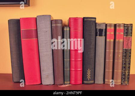 Alte Bücher über Holzregal. Antike Bücher auf gelb und rot Hintergrund Stockfoto