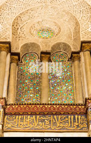 Zwei benachbarte perforierte Stuckbogenfenster mit farbenfrohen Glasmustern im Qalawun-Komplex, Kairo, Ägypten Stockfoto