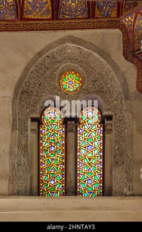 Zwei benachbarte perforierte Stuckbogenfenster mit farbenfrohen Glasmustern im Qalawun-Komplex, Kairo, Ägypten Stockfoto