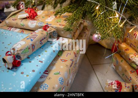 Festliche eingewickelte Weihnachtsgeschenke und Weihnachtsgeschenke unter dem Weihnachtsbaum zeigt dekorative Unboxing-Veranstaltung mit traditionellen Feier der handgefertigten Wintersaison für funkelnde Kinder Augen Schönheit Stockfoto