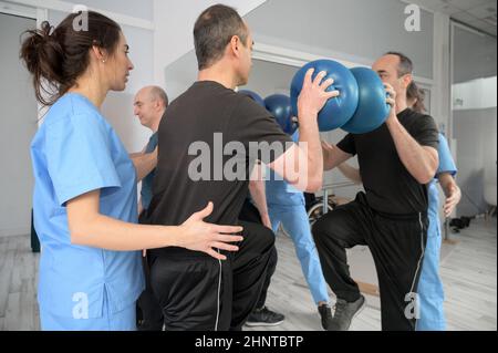 Gruppe von Menschen mit Behinderung Ausübung in der Rehabilitationsklinik. Stockfoto