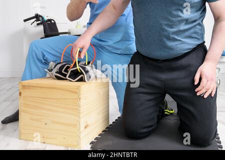 Mann mit Behinderung macht Genesungsübung mit Hantel. Mann mit Ataxie bei der Genesungsunterstützung Therapie Physiotherapie Gesundheitssystem. Stockfoto