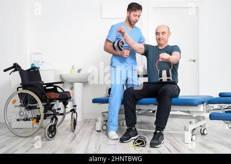 Mann mit Behinderung macht Genesungsübung mit Hantel. Mann mit Ataxie bei der Genesungsunterstützung Therapie Physiotherapie Gesundheitssystem. Stockfoto