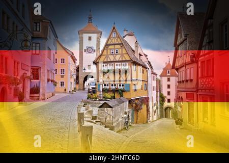 Kopfsteinpflasterstraße und Architektur der historischen Stadt Rothenburg ob der Tauber mit Blick auf die deutsche Flagge Stockfoto