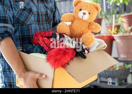 Halten Sie Kleidung Spendenbox mit gebrauchter Kleidung und Puppe zu Hause, um Hilfe für arme Menschen in der Welt zu unterstützen. Stockfoto