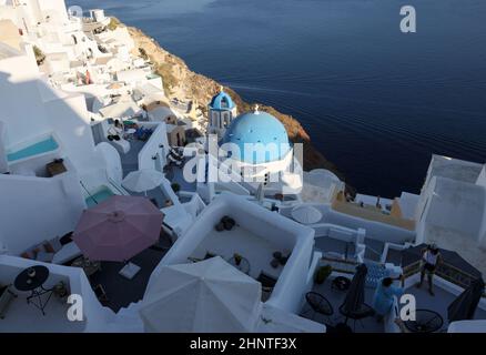 Blick vom Aussichtspunkt auf das Dorf Oia mit der blauen Kuppel der griechisch-orthodoxen christlichen Kirche und der traditionellen, weiß getünchten griechischen Architektur. Santorini, Griechenland Stockfoto