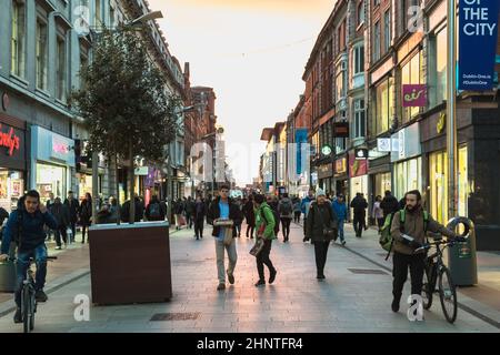 Menschen, die eine Einkaufsstraße in Dublin, Irland, entlang laufen Stockfoto