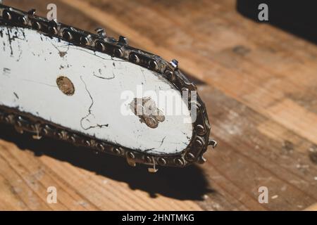 Kettensägebalken und Schneidekette schließen sich an. Blatt einer Kettensäge auf Holzhintergrund Stockfoto