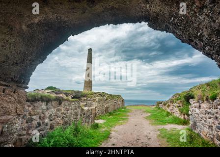 Ein alter Pfad, gesäumt von Steinmauern, verläuft vom Eingang des alten kornischen Steintunnels zum Rand der Klippen und dem Meer dahinter. Stockfoto