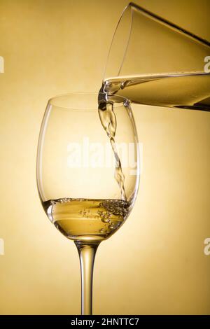 Gießen Sie Weißwein aus einer Karaffe in ein Weinglas Stockfoto