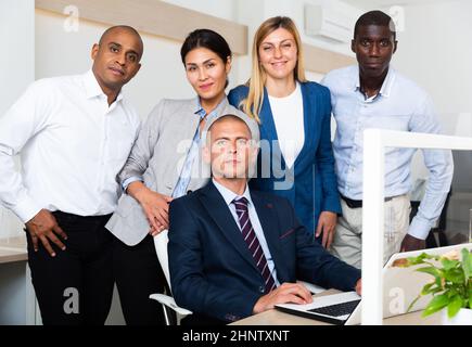 Porträt einer fröhlichen, positiven und erfolgreichen multinationalen Unternehmensgruppe im Zimmer Stockfoto