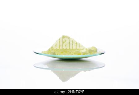 Schwefelpulver in chemischem Uhrenglas. Nahaufnahme des chemischen Inhaltsstoffs auf dem weißen Labortisch. Seitenansicht Stockfoto