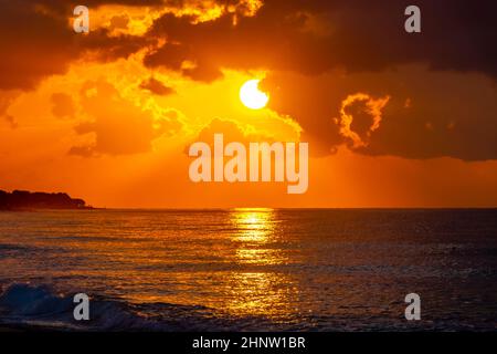 Goldene Farben des schönsten Sonnenuntergangs am Strand von Ialysos auf der griechischen Insel Rhodos. Stockfoto