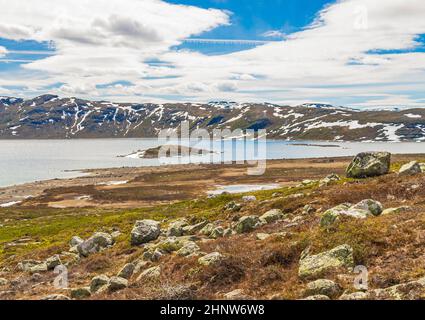 Erstaunliches Vavatn Seenpanorama raue Landschaft Blick Felsen Felsbrocken und Berge mit Schnee im Sommer in Hemsedal Norwegen. Stockfoto