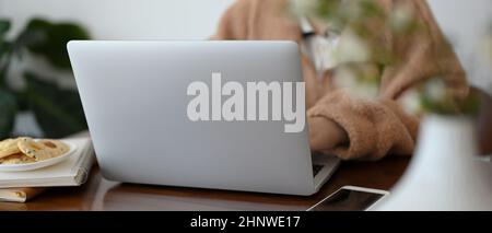 Nahaufnahme für Präsentationshintergrund, Eine Frau in kuscheligem braunen Pullover, die am Laptop-Computer im Café arbeitet. Stockfoto