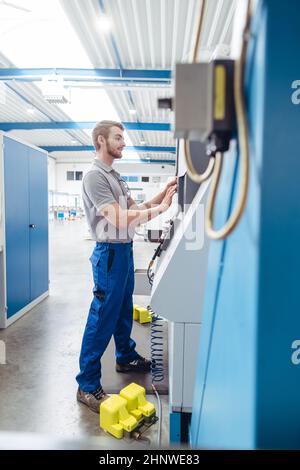 Fertigungsmitarbeiter programmieren industrielle CNC-Werkzeugmaschine bei der Eingabe von Arbeitsdaten Stockfoto