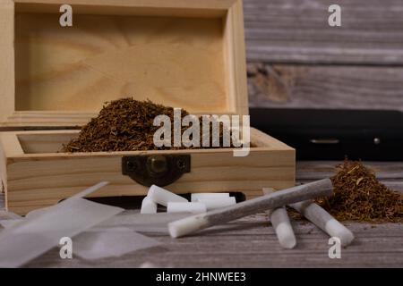 Handrolltabak auf einem Holztisch und Zigaretten Stockfoto