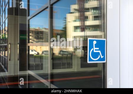 Der Aufkleber, der den Eingang für Behinderte auf dem Glas einer Tür anzeigt Stockfoto