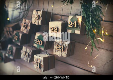 Hausgemachte kleine Kartonschachteln für Adventsurbrisen mit Feenlicht. Hängender Vintage Adventskalender aus Karton für ein umweltbewusstes c Stockfoto