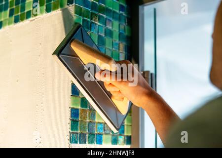 Bauarbeiter, der keramische Mosaikplatten auf flexiblem Klebstoff installiert. Stockfoto