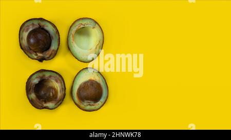 Zwei schlechte Avocado. Hässliches Essen auf gelbem Hintergrund. Verfaulte tropische Früchte. Konzept der faulen Frucht. Platz auf gelbem Hintergrund kopieren. Stockfoto