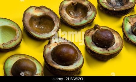 Die Hälfte verrottete Avocados auf dem gelben Tisch. Unhelthy Food-Konzept. Nahaufnahme schlechter Avocado auf gelbem Hintergrund. Stockfoto