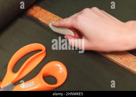 Schneiderei markiert Textilien mit Seife und Holzlineal auf Musterschnitt. Stockfoto