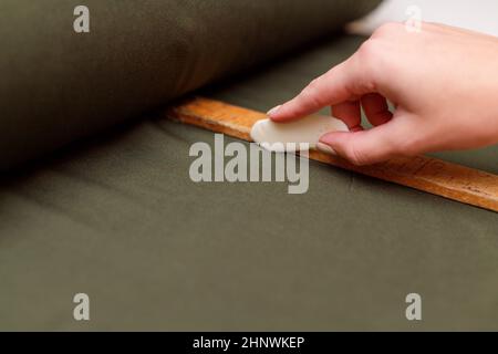 Schneiderei markiert Textilien mit Seife und Holzlineal auf Musterschnitt. Stockfoto