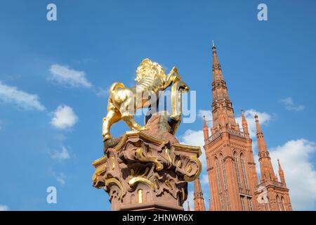 Goldener Nassauer Löwe am Marktbrunnen in Wiesbaden, Deutschland mit Spitze der Marktkirche Stockfoto